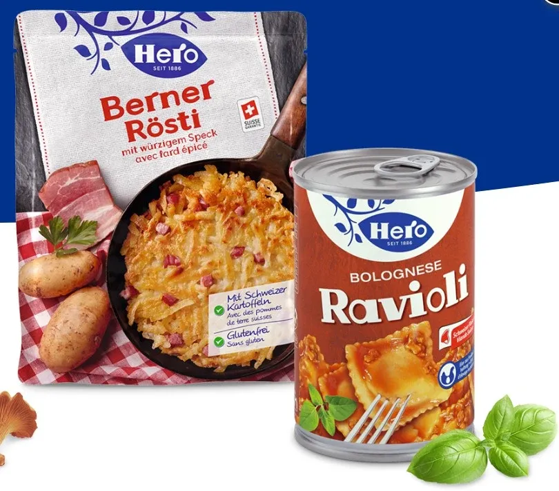 Bild einer Hero Konserverbüchse. Im Hintergrund Hero Rösti in der Verpackung.